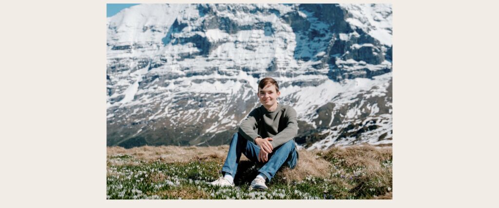 Teen boy sitting with Eiger in background
