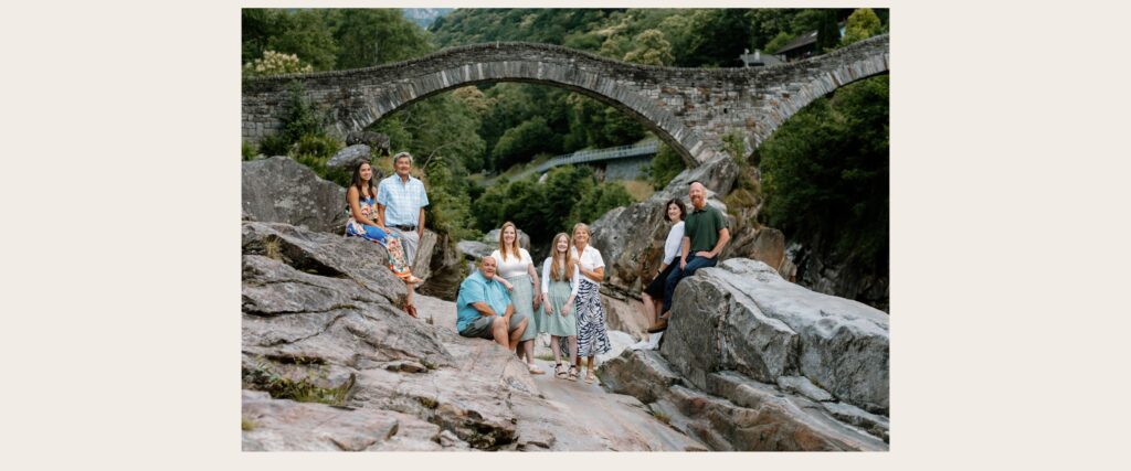 Large group family portrait at the Ponte dei Salti bridge in Valle Verzasca, Ticino, Switzerland during a sunrise photoshoot.