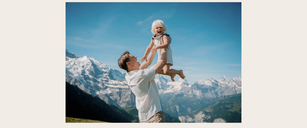 Father lifting son during a family photos Lauterbrunnen session with Swiss Alps behind them