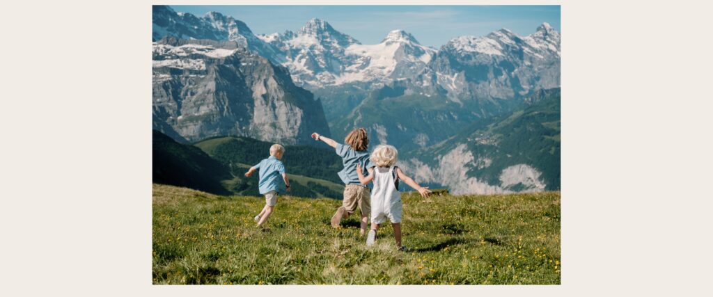 Children running through an Alpine meadow during a Lauterbrunnen family photos session with Swiss mountain views