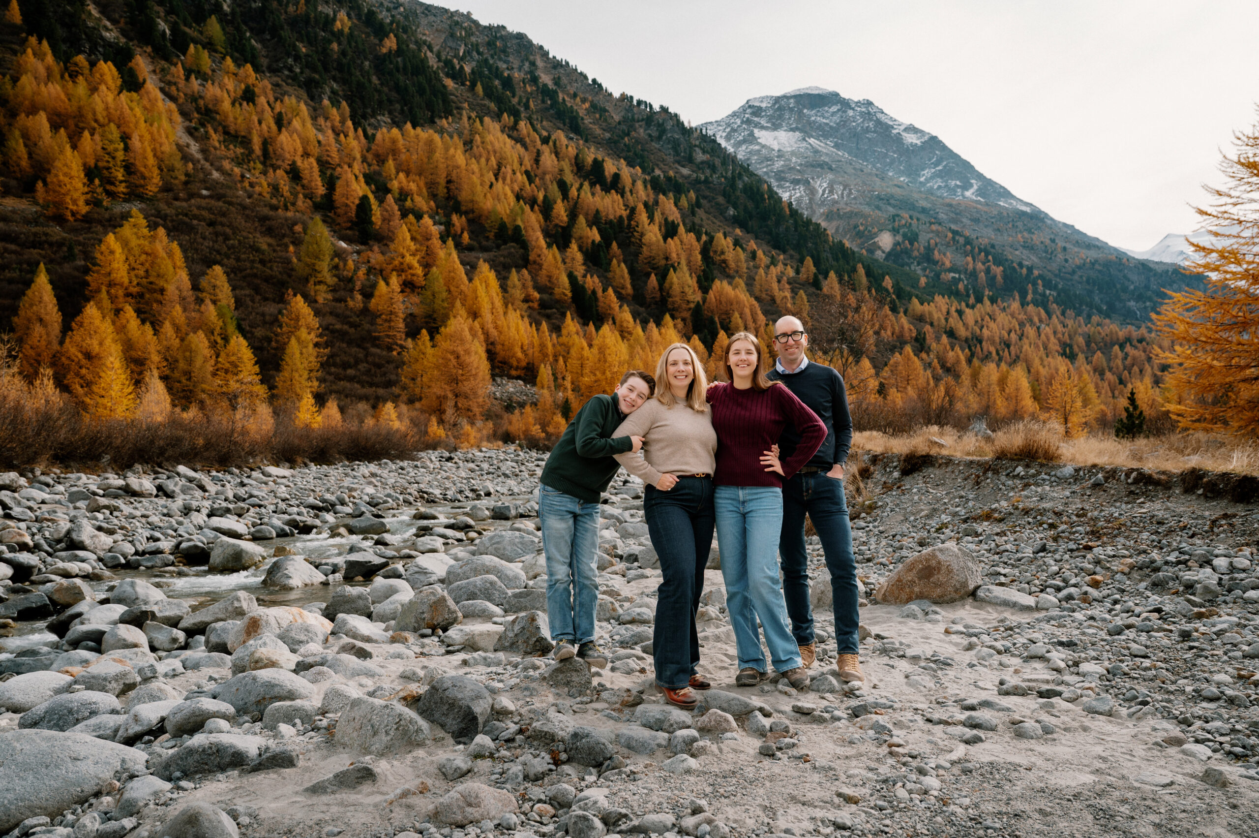 Family standing together in a rocky alpine valley during golden larch season with glacier views in Switzerland