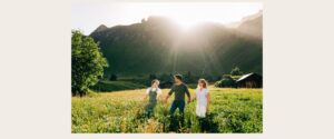 Family walking through a sunlit golden hour mountain valley with alpine peaks rising behind them in the Jungfrau Region of Switzerland