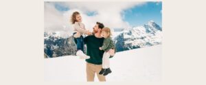 Father holding two children during a family photo session in the Jungfrau region, reflecting the visitor experience Jungfrau region offers in winter conditions.