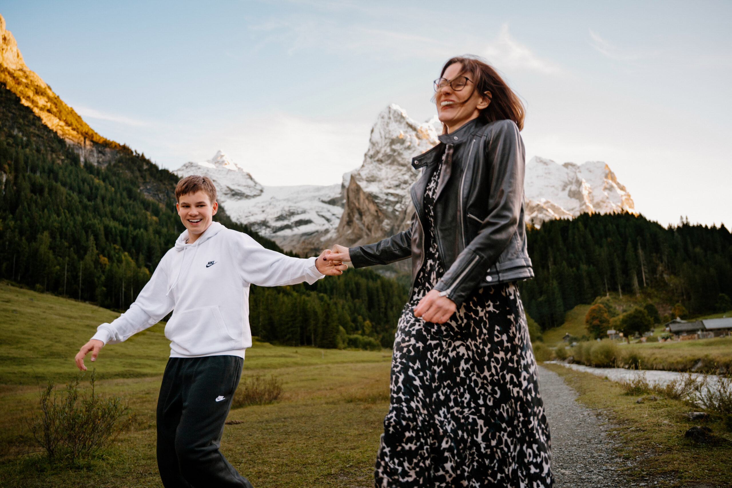 Family walking on a scenic path in the Swiss Alps with mountain views, showing an accessible location where no permit is required for photos